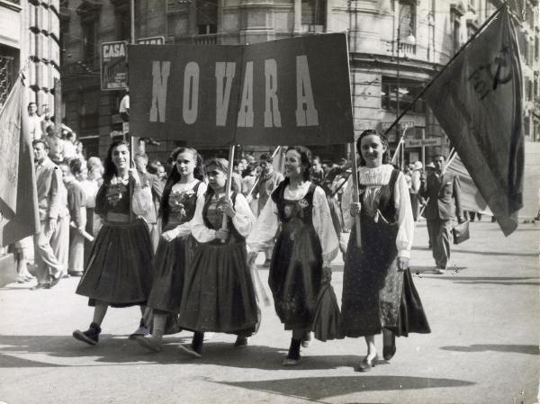 Roma - Festa nazionale de l'Unità 1948 - Sfilata per le vie della città - Spezzone di corteo con ragazze in costume recanti uno striscione con la scritta "Novara"- Bandiere - Cartelli