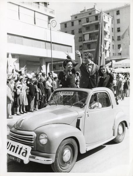 Genova - Festa nazionale de l'Unità 1950 - Sfilata per le vie della città - Spezzone di corteo con la rappresentanza de l'Unità di Torino - Automobile trasporta alcuni compagni in piedi con il pugno alzato - Ritratto di gruppo - Cartelli