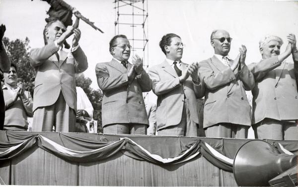 Bologna - Festa nazionale de l'Unità 1951 - Tribuna del Comitato Centrale del PCI - Da sinistra: Luigi Longo, Palmiro Togliatti, Pietro Secchia, Celeste Negarville, Giuseppe Dozza - Ritratto di gruppo - Bandiere - Megafono
