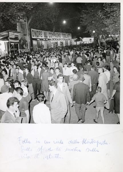 Bologna - Festa nazionale de l'Unità 1964 - Veduta notturna della folla che passeggia tra i viali - Sullo sfondo la mostra all'aperto sulla vita di Palmiro Togliatti - Striscioni - Cartelli