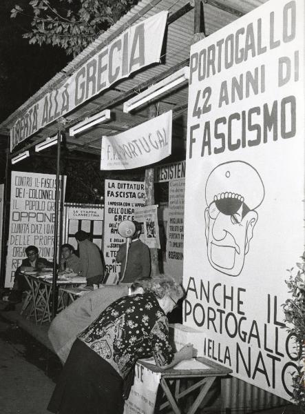 Bologna - Festa nazionale de l'Unità 1968 - Raccolta di firme contro il fascismo in Grecia e in Portogallo - Due persone firmano una petizione - Cartelli di protesta - Uomo parla al megafono