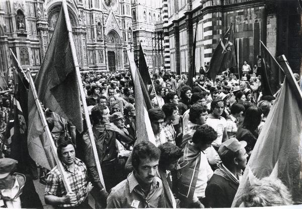 Firenze - Festa nazionale de l'Unità 1975 - Sfilata per le vie della città  - Spezzone di corteo transita in piazza del Duomo - Striscioni - Bandiere - Sullo sfondo la cattedrale di Santa Maria del Fiore e il Battistero