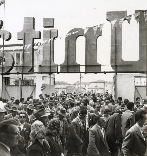 Modena - Festa nazionale de l'Unità 1957 - Piazza d'Armi - Folla a un ingresso - Scritta "Unità" su struttura metallica -