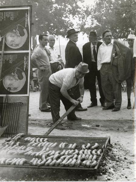 Modena - Festa nazionale de l'Unità 1966 - Un volontario prepara da mangiare sulla griglia all'aperto - Cibo - Cartelli - Ritratto di gruppo