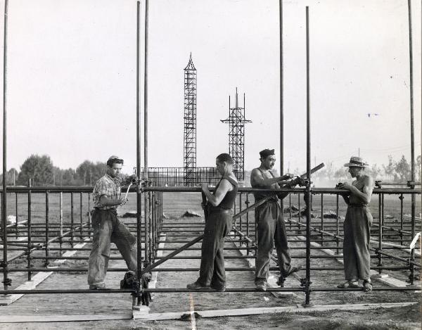 Milano - Festa nazionale de l'Unità 1953 - Parco Lambro - Operai montano delle strutture metalliche - Sullo sfondo due torri