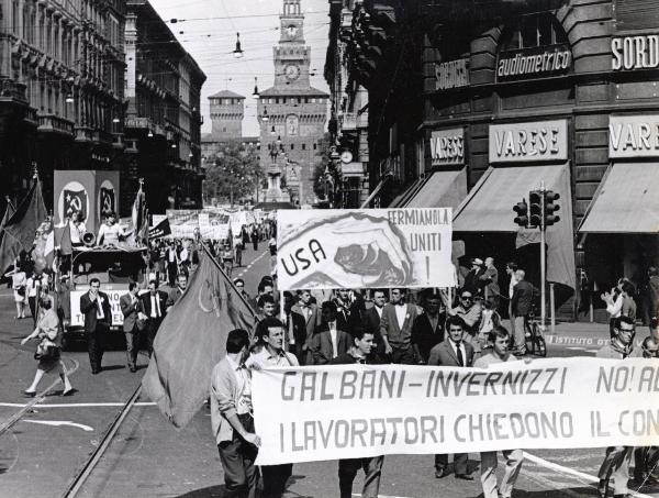 Milano - Festa nazionale de l'Unità 1967 - Via Dante - Manifestazione di chiusura - Spezzone di corteo con vari cartelli di protesta - Camion con manifestanti e simboli del PCI - Megafono - Striscioni - Bandiere - Sullo sfondo il Castello Sforzesco