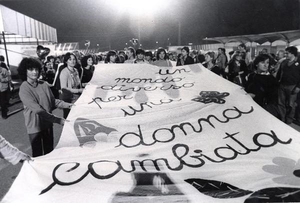 Bologna - Festa nazionale de l'Unità 1980 - Corteo notturno - Un gruppo di donne regge uno striscione con la scritta "un mondo diverso per una donna cambiata"