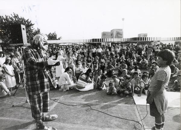 Bologna - Festa nazionale de l'Unità 1980 - Spettacolo per bambini - Un clown si esibisce davanti al pubblico - Cartelli