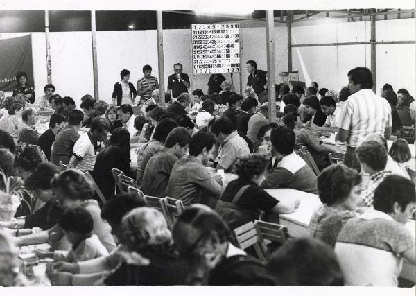 Bologna - Festa nazionale de l'Unità 1980 - La tombola - Folla partecipa all'estrazione dei numeri - Uomo al microfono - Cartello