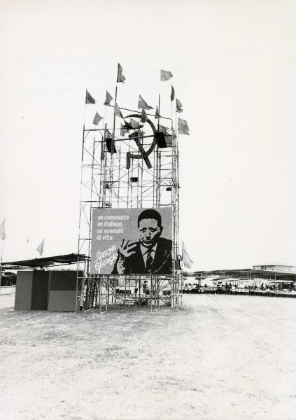 Ferrara - Festa provinciale de l'Unità 1980 - Struttura metallica a torre con cartello recante il ritratto di Giorgio Amendola, scritte, bandiere e simbolo di falce e martello