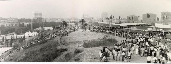 Roma - Festa nazionale de l'Unità 1984 - EUR - La folla in fila nella zona dei ristoranti - Bandiere - Cartelli - Sullo sfondo a sinistra il palazzo della Civiltà Italiana