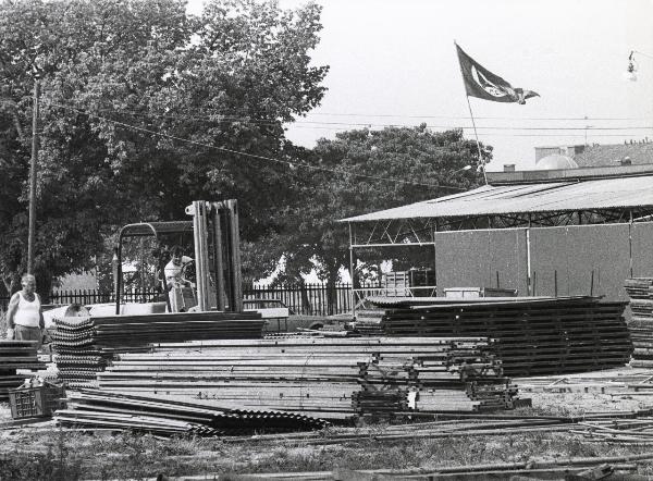 Milano - Festa provinciale de l'Unità 1984 - Monte Stella - Allestimento - Operaio su mezzo meccanico al lavoro - Strutture e materiali - Bandiera