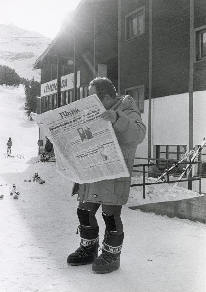 Bormio - VI Festa nazionale de l'Unità sulla neve 1984 - Un uomo legge una copia del giornale - Cartello