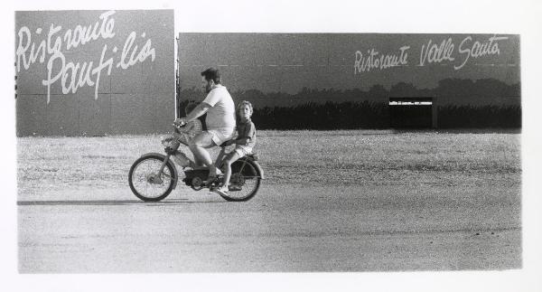 Ferrara - Festa nazionale de l'Unità 1985 - Aeroporto militare - Un uomo e due bambini su una motocicletta - Ritratto di gruppo - Stand - Scritte