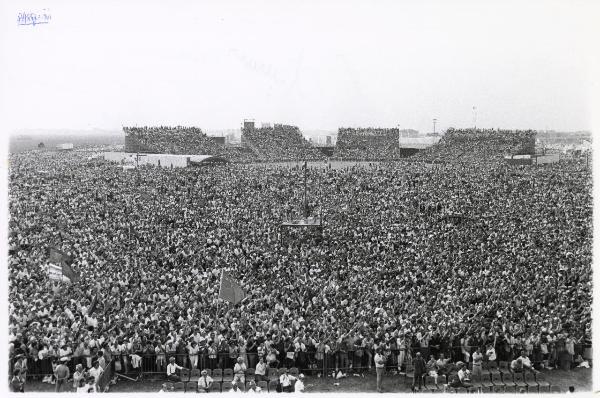 Ferrara - Festa nazionale de l'Unità 1985 - Aeroporto militare - Arena - Manifestazione di chiusura - La folla - Al centro cineoperatori e fotografi riprendono l'evento - Bandiere