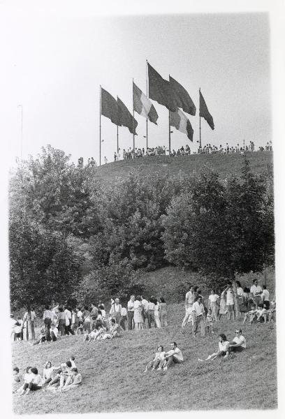 Milano - Festa provinciale de l'Unità 1985 - Monte Stella - Scorcio della sommità con grandi bandiere - Folla a passeggio - Gruppi di persone sedute sul prato