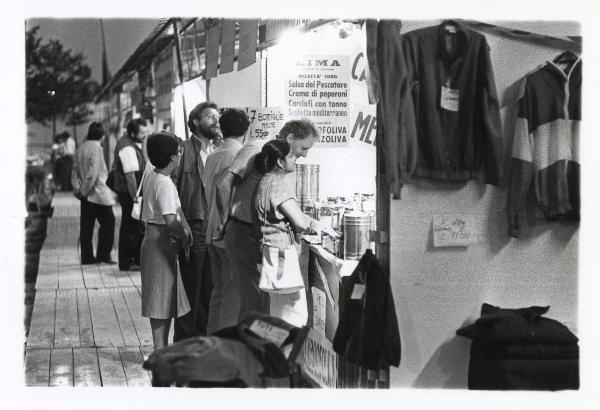 Milano - Festa provinciale de l'Unità 1985 - Monte Stella - "Centro commerciale" - Stand alimentare - Alcune persone acquistano prodotti          tipici - Abiti - Cartelli