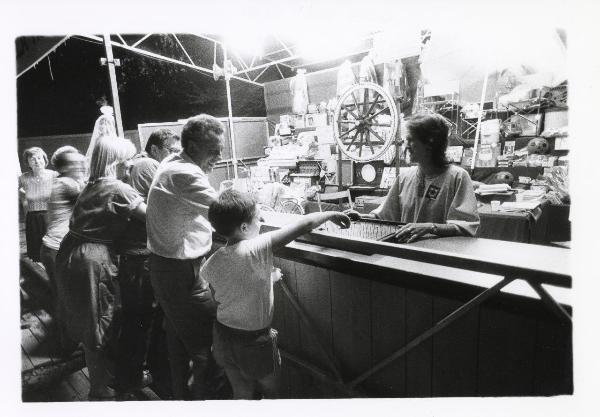 Milano - Festa provinciale de l'Unità 1985 - Monte Stella - Gioco della ruota - Un bambino sceglie il numero - Addetta al banco - Visitatori - Illuminazione