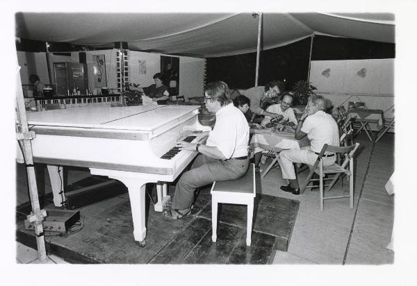 Milano - Festa provinciale de l'Unità 1985 - Monte Stella - Il piano bar - Musicista al pianoforte - Gruppo di persone intorno a un tavolo - Ritratto di gruppo - Cartelli