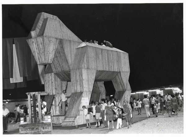 Modena - Festa provinciale de l'Unità 1982 - Una grande struttura in legno a forma di cavallo viene trainata da un mezzo da lavoro - Folla - Bambini - Cartello - Stand