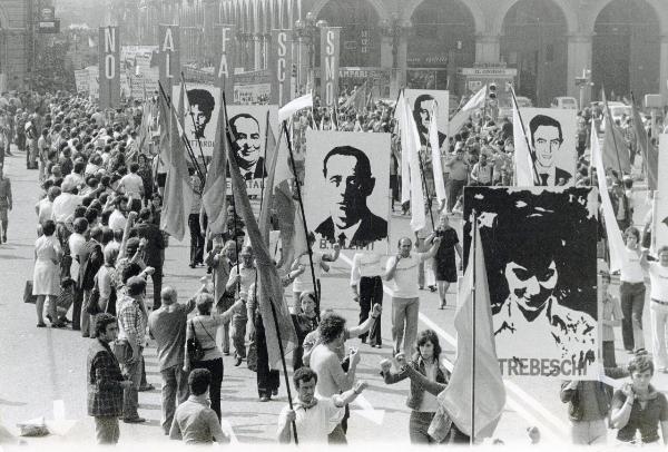 Bologna - Festa nazionale de l'Unità 1974 - Sfilata per le vie della città - Spezzone di corteo con le immagini delle vittime della strage di Piazza della Loggia a Brescia del 28 maggio 1974 - La folla saluta con il pugno alzato - Bandiere - Cartelli