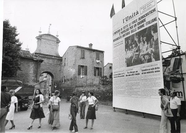 Ferrara - Festa nazionale de l'Unità delle Donne 1977 - Porta della città - Struttura metallica con gigantografia di una pagina del giornale - Persone a passeggio