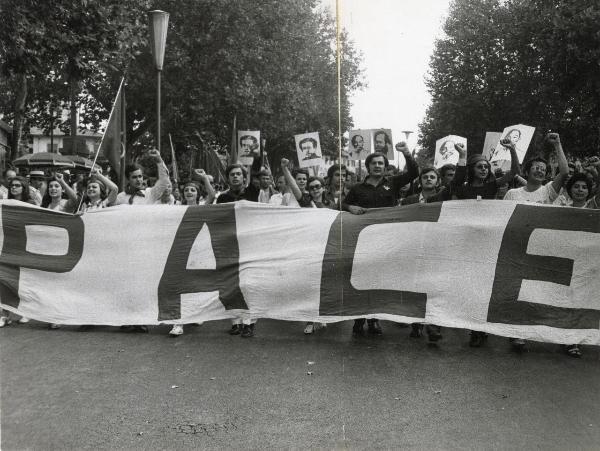 Firenze - Festa nazionale de l'Unità 1970 - Sfilata per le vie della città - Spezzone di corteo con striscione a favore della pace in Vietnam - Cartelli con ritratti di Gramsci e Ho Chi Min - Manifestanti con il pugno alzato - Bandiere