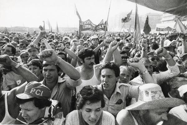 Genova - Festa nazionale de l'Unità 1978 - Fiera del Mare - Manifestazione conclusiva - Compagni con il pugno alzato ascoltano il discorso di Enrico Berlinguer - Ritratto di gruppo - Striscioni - Bandiere