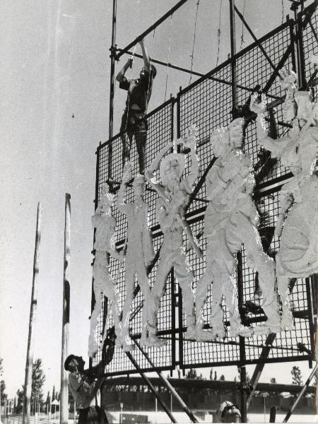 Modena - Festa provinciale de l'Unità 1956 - Costruzione dell'ingresso principale - Operai al lavoro su una grande struttura metallica - Bandiere