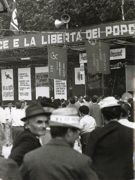 Modena - Festa nazionale de l'Unità 1966 - Folla a passeggio tra gli stand - Cartelli con scritte - Striscione - Bandiere - Altoparlanti