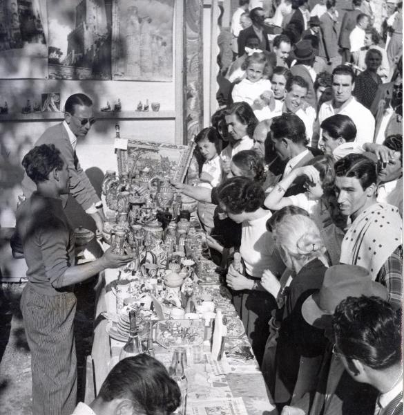 Milano - Festa nazionale de l'Unità 1953 - Parco Lambro - Stand della Sicilia - Banco di prodotti artigianali - Addetti alla vendita - Folla di visitatori