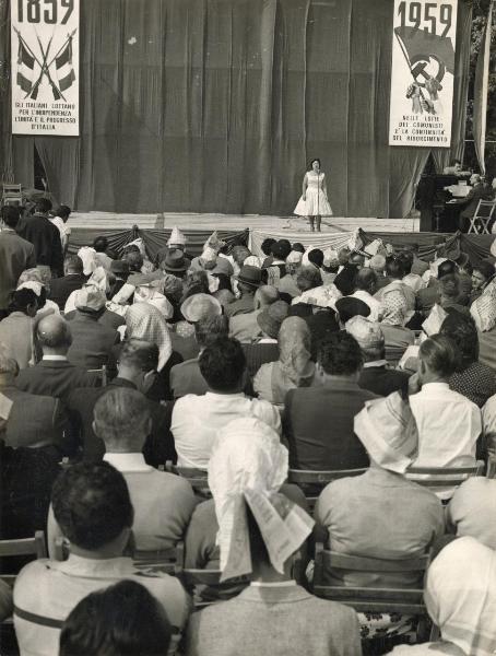 Milano - Festa provinciale de l'Unità 1959 - Parco Lambro - Spettacolo canoro - Palco - Cantante al microfono accompagnata dal pianista - Cartelli con scritte e simboli - Pubblico