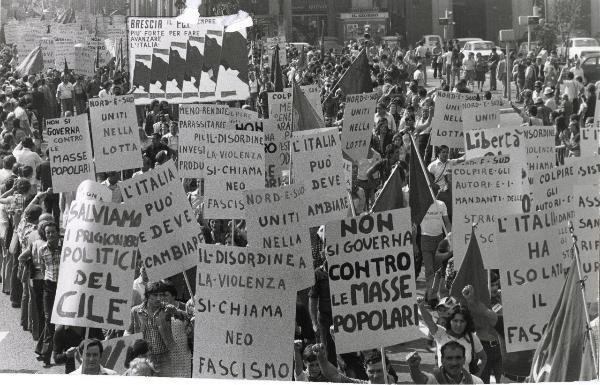 Milano - Festa provinciale de l'Unità 1974 - Sfilata per le vie della città - Spezzone di corteo con manifestanti che portano cartelli di protesta - Bandiere - Automobili