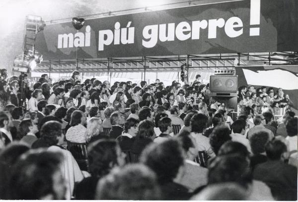 Bologna - Festa nazionale de l'Unità 1980 - Parco Nord - Pubblico assiste a uno spettacolo - Grande striscione sorretto da struttura metallica - Illuminazione