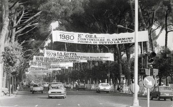 Roma - Festa nazionale de l'Unità delle Donne 1980 - Striscioni appesi in un viale alberato - Traffico - Automobili - Cartelli - Semaforo