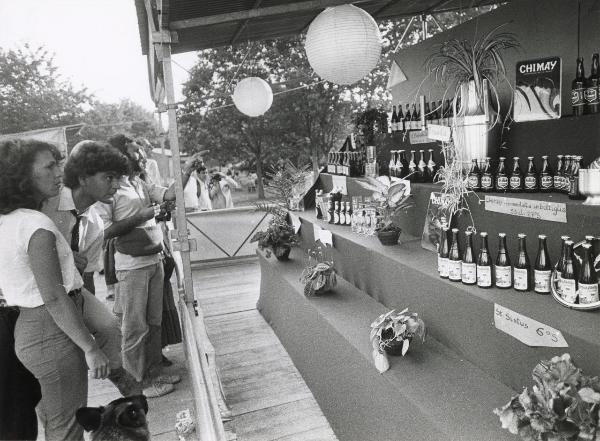 Milano - Festa provinciale de l'Unità 1981 - Monte Stella - La "birroteca" - Banco di vendita - Visitatori osservano delle bottiglie esposte - Ritratto Cartelli