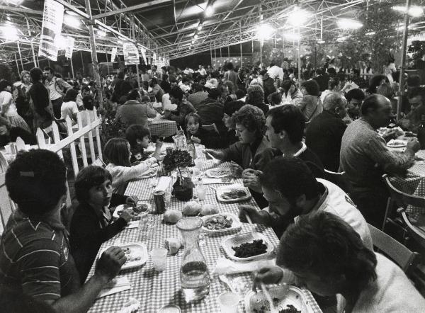 Milano - Festa provinciale de l'Unità 1981 - Monte Stella - Interno di un ristorante - Tavolate con adulti e bambini - Illuminazione -  Strutture metalliche - Cartelli