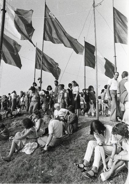 Milano - Festa provinciale de l'Unità 1981 - Monte Stella - Grandi bandiere rosse e tricolori sventolano sulla sommità della collinetta - Folla seduta sul prato e a passeggio