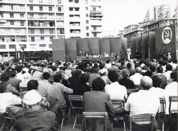 Genova - Festa provinciale de l'Unità 1981 - Dibattito politico - Palco - Un oratore al microfono - Pubblico - Architettura - Cartello