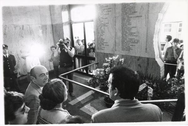 Bologna - Festa nazionale de l’Unità delle donne 1982 - Stazione - Sala d'attesa - La presidente della Camera Nilde Iotti di fronte alla lapide che ricorda i nomi delle vittime della strage del 2 agosto 1980 - Cineoperatore - Fiori