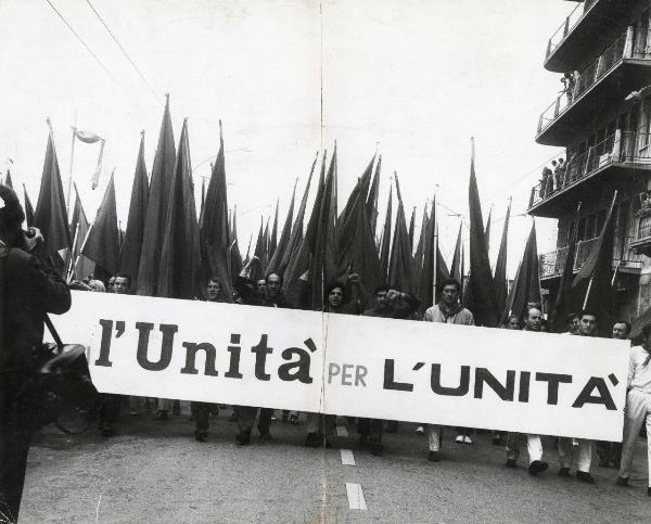 Livorno - Festa nazionale de l'Unità 1969 -  Manifestazione di chiusura - Sfilata in onore di Ho Chi Min - Spezzone di corteo con operai recanti lo striscione de l'Unità - Bandiere - Persone affacciate ai balconi