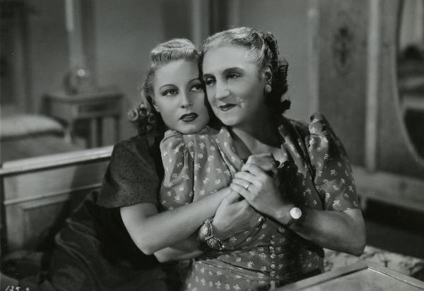 Scena del film "La famiglia Brambilla in vacanza" - Regia Carl Boese, 1941 - Scena d'interno: Helen Lüber, a sinistra, abbraccia da dietro Amelia Chellini, a destra. Entrambe le attrici sono sedute.
