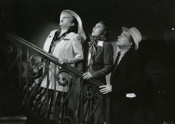 Scena del film "La famiglia Brambilla in vacanza" - Regia Carl Boese, 1941 - Il papà, la mamma e la nanà interpretati in sequenza da Cesco Baseggio, Amelia Chellini e Helen Lüber in fila indiana appoggiati su una scala mentre guardano verso l'alto.