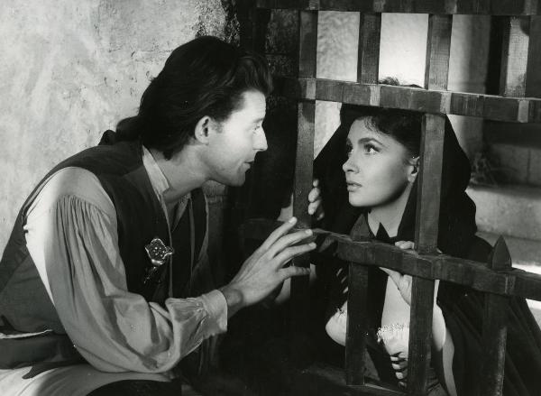 Scena del film "Fanfan la tulipe" - Regia Jacques, Christian, 1952 - Separati dalle sbarre di una cella, Philipe Gérard avvicina la mano destra e rivolge lo sguardo verso Gina Lollobrigida, a destra con il capo coperto, che lo ricambia.
