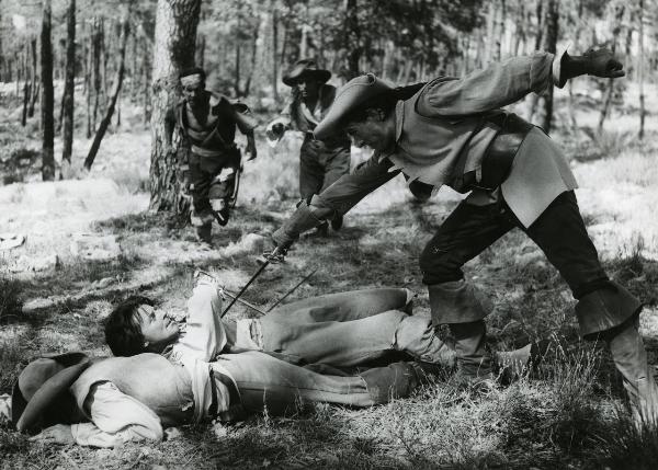 Scena del film "Fanfan la tulipe" - Regia Jacques, Christian, 1952 - Al fianco di un attore non identificato, steso prono, Philipe Gérard, supino, si difende con una spada dall'attacco di un attore non identificato che si protrae verso di lui.