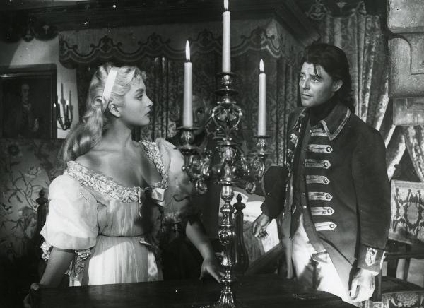 Scena del film "Fanfan la tulipe" - Regia Jacques, Christian, 1952 - Geneviève Page, a sinistra, appoggiandosi a un mobile rivolge lo sguardo verso Philipe Gérard, a destra, che la osserva.