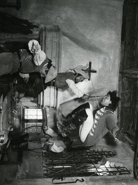 Scena del film "Fanfan la tulipe" - Regia Jacques, Christian, 1952 - Philipe Gérard, balzando sopra un tavolo, schiva la lama della spada di un attore non identificato davanti a lui e para il colpo di spada di un altro attore non identificato.