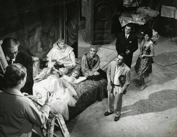 Sul set del film "Fantasmi a Roma" - Regia Pietrangeli, Antonio, 1961 - Su un letto sono sdraiati Sandra Milo e un attore non identificato, con a sinistra Buazzelli e a destra Gassman. A destra, Mastroianni guarda verso l'alto, come Claudio Gora.