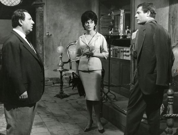 Scena del film "Fantasmi a Roma" - Regia Pietrangeli, Antonio, 1961 - Marcello Mastroianni, a destra, é osservato da Belinda Lee, al centro che nel mentre conversa con un attore non identificato di profilo, a sinistra.
