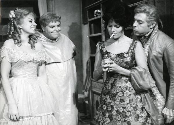 Scena del film "Fantasmi a Roma" - Regia Pietrangeli, Antonio, 1961 - Mentre Belinda Lee, a destra, è intenta ad accendersi una sigaretta, Mastroianni cerca di spegnere la fiamma soffiando. A sinistra, Sandra Milo e Buazzelli osservano la scena.
